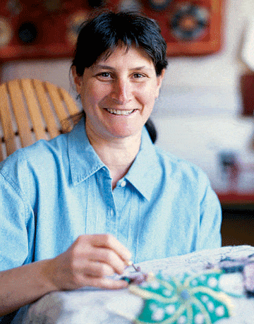 woman in blue shirt working on hooked rug
