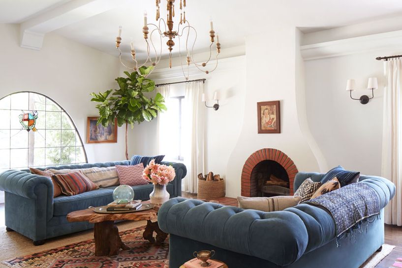 white living room with spanish style fireplace and two blue chesterfield sofas