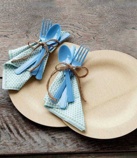 a pair of bamboo plates with blue plastic utensils tied with a napkin and twine