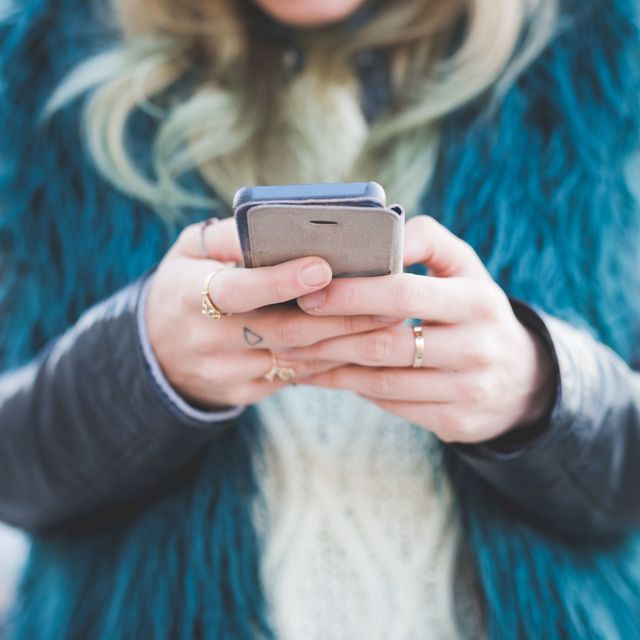 Cropped photo of woman with rings texting on smartphone