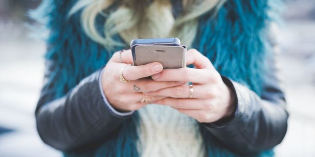 Cropped photo of woman with rings texting on smartphone