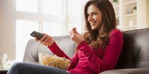 Vrouw kijkt tv op bank met popcorn