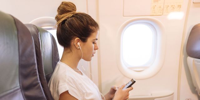 Vrouw in vliegtuig met mobiel