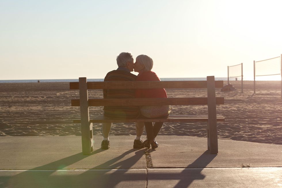 Old couple kissing on a bench