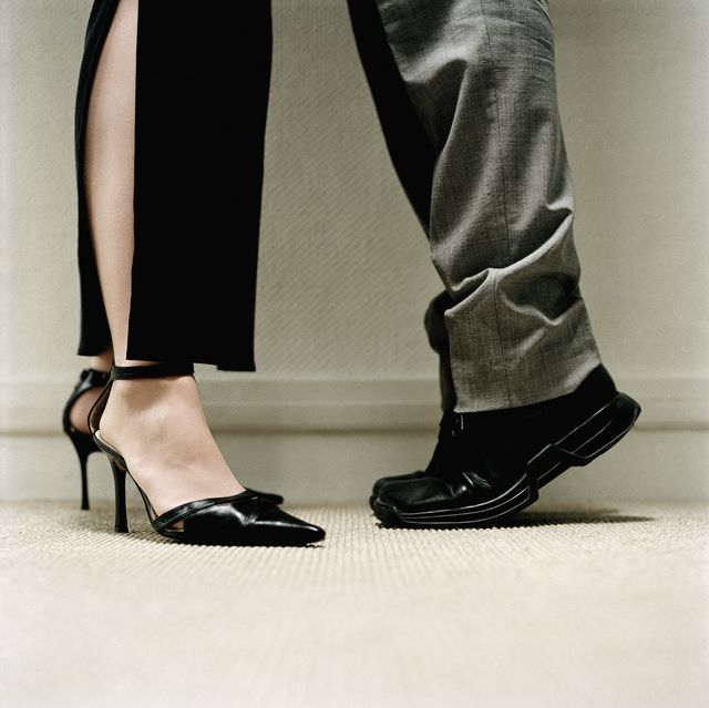 Man's feet on tiptoes standing in front of a woman's feet in heels