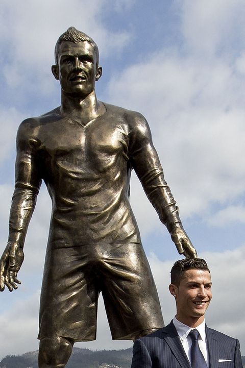 Cristian Ronaldo stands with his new statue, which happens to have a massive penis bulge.