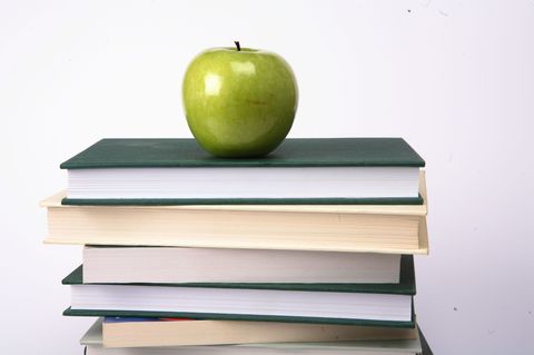 Pile of school books with an apple on top