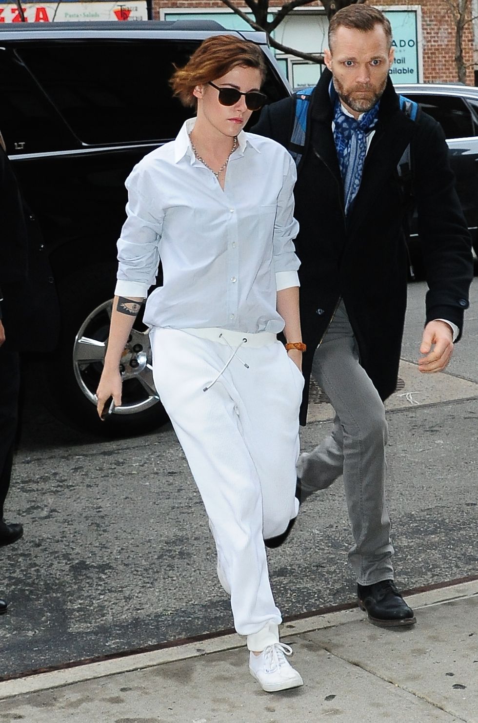 Kristen Stewart wearing pale blue shirt and white relaxed joggers