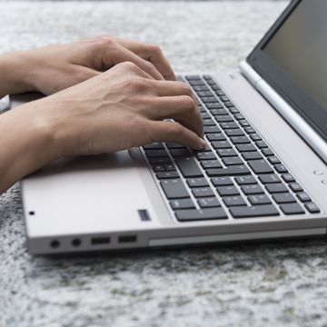 Hands typing on laptop
