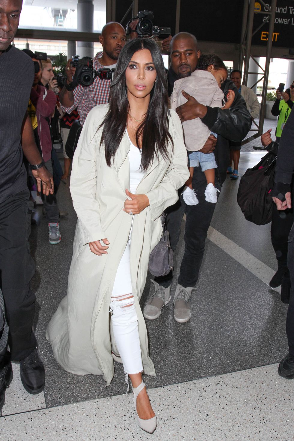 Kim Kardashian wearing cream duster coat in the airport