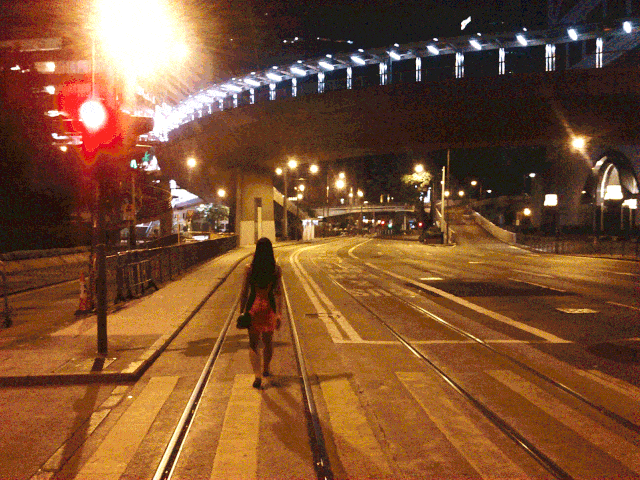 Woman walking under a bridge at night