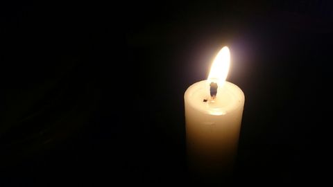 Candle burning on black background