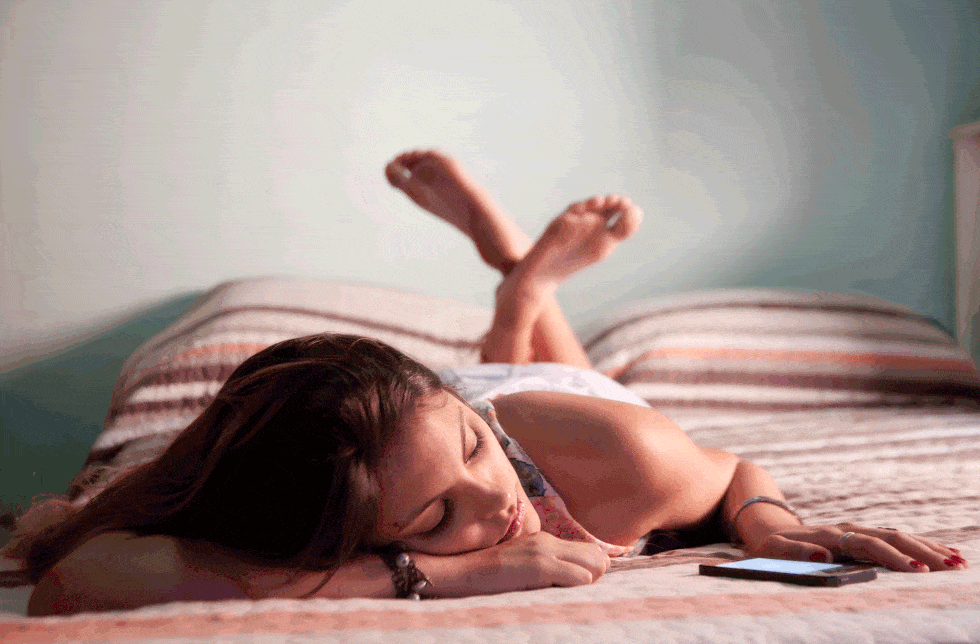 woman relaxing alone on bed with phone