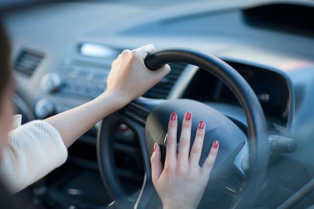 Woman with her hand on steering wheel