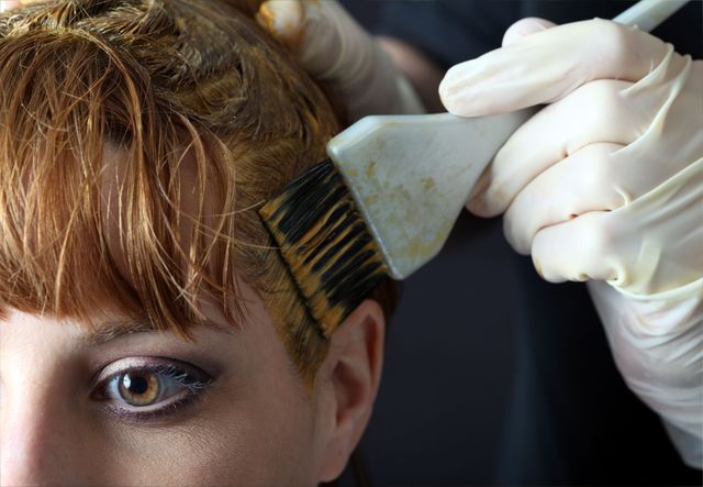 Hairdresser applying hair colour to woman