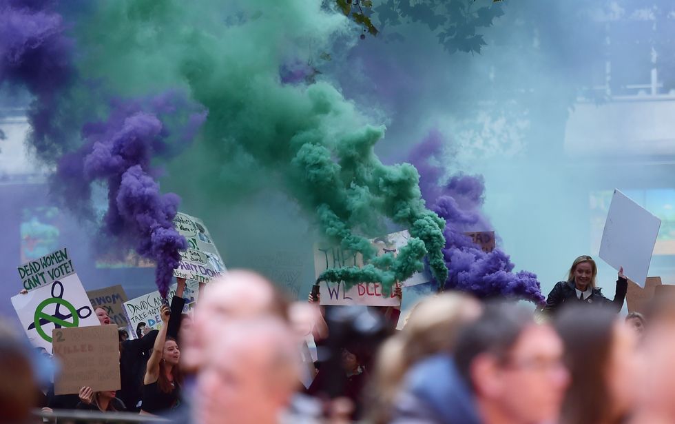 Domestic violence campaigners let off smoke bombs in protest of government cuts at the Suffragette BFI London premiere