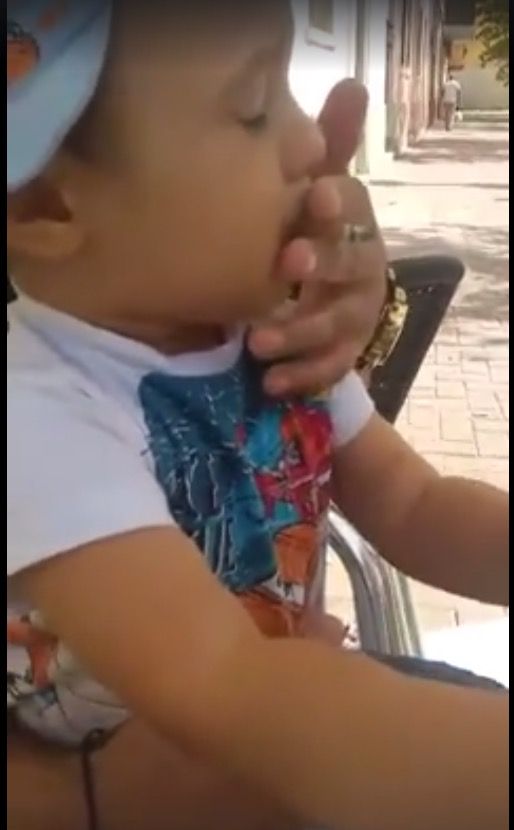 Baby being force fed a cigarette