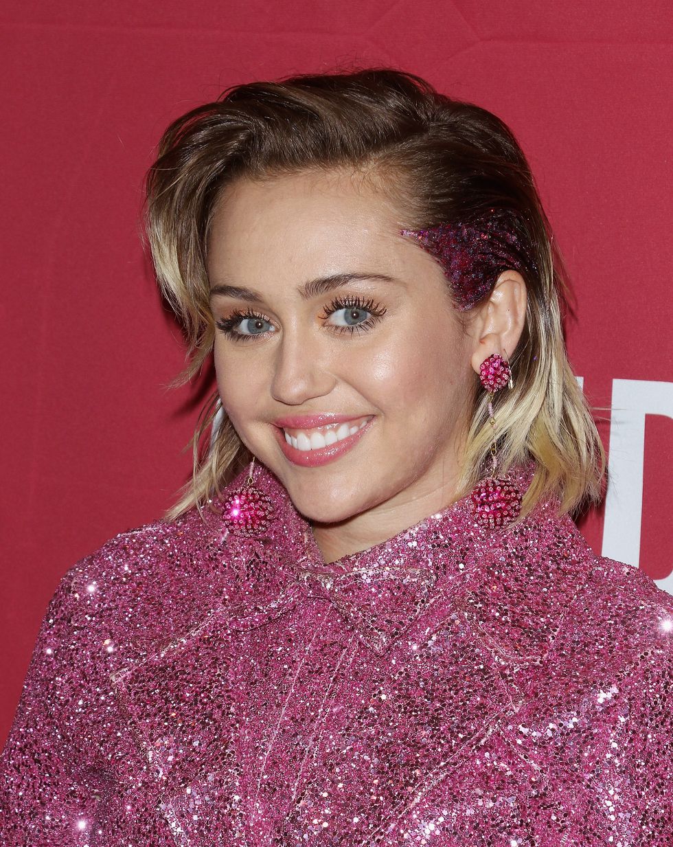 Miley Cyrus wearing pink glitter at a concert to mark World Aids Day