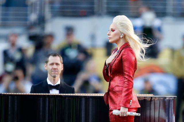 Lady Gaga wearing a custom Gucci red suit while performing the National Anthem at the Super Bowl 2016