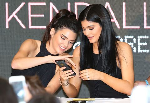 Kendall and Kylie Jenner swiping on a phone