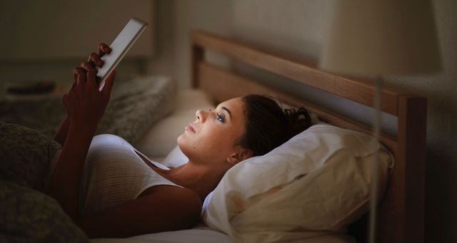 Girl reading Kindle in bed