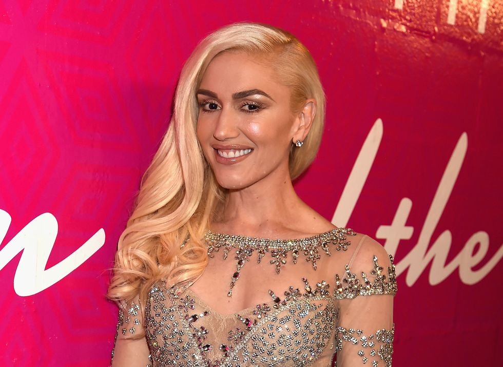 gwen stefani poses with long blonde hair and sparkling sheer gown at red carpet event