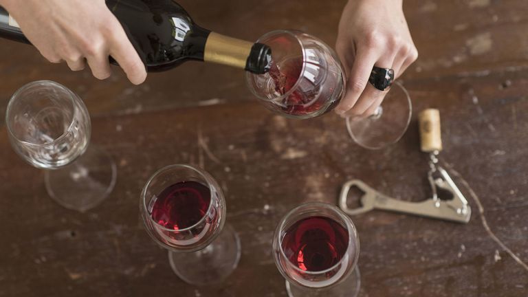 pouring red wine into glasses