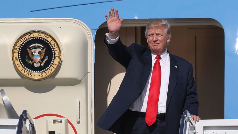 President Donald Trump waves as he arrives on Air Force One at the Palm Beach International Airport to spend part of the weekend at Mar-a-Lago resort.