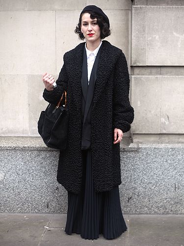 <p>Despite bold, bright colours being the go-to trend this season, this fashionista opted for a layered black look instead – and totally pulled it off. The pleated skirt, retro curls and red lips made this lady stand out from the crowd</p>