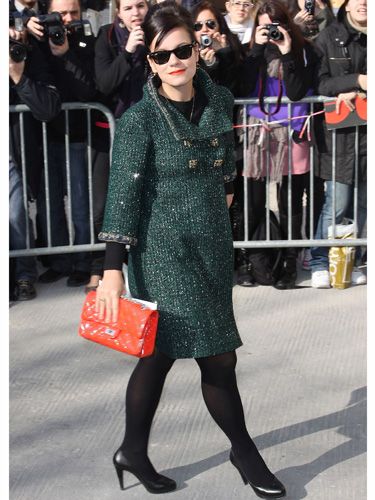 <p>Lily arrived at the Chanel show wearing a divine moss green tweed coat by the luxe label and carrying one of their tangerine coloured quilted shoulder bags which matched her stand-out lippy</p>