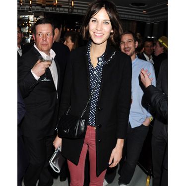 <p>Alexa Chung looks stylish with her Bordeaux coloured slim trousers combined with a white spotted marine top and a mid-length black coat that matches her shoes. A complex combination but a simple on-trend look</p>