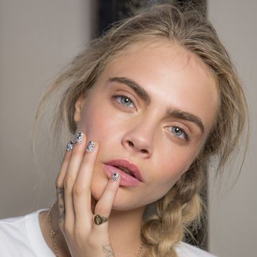 <p>The look was raw and minimal at Giles (except for blinging Swarovski crystal-studded nail art created by Marian Newman), and Cara was the perfect canvas for the "90s supermodel with no makeup" look created by makeup artist Lucia Pica. Contouring came courtesy of the <a href="http://www.cosmopolitan.co.uk/beauty-hair/beauty-tips/hair-products-makeup-experts-recommend" target="_blank">MAC Spring/Summer 2014 Forecast Palette</a> (on sale now) and her rose bud lip was thanks to the forthcoming MAC Aim To Please Velvetease Lip Pencil. Cara's hair looked amazing in the matte texture braid created by the TONI&GUY session team.</p>