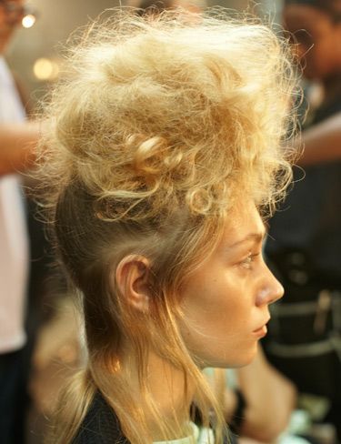 <p><strong>The hair look:</strong> Styled by global ghd creative director Sam McKnight and his team, hair was reminiscent of Greek statues with major backcombing for tall statuesque silhouettes.</p>
<p><strong>Get the look:</strong> 1) Using the ghd tail comb, take out the hairline from temple to temple, leaving a soft airy section around the hairline. 2) Gather all the remaining hair into a high pony at the top of the head, using the ghd oval dressing brush to smooth for a sleek finish. Secure with an elastic band. 3) Take small sections of hair from the pony at a time and wrap around one finger. Once wrapped, gently release your finger holding the curl in place. Using the ghd eclipse styler, close onto the curl and hold for approximately five seconds, then pin up and leave to cool. 4) Once repeated throughout the whole ponytail, release the pins and brush through the hair to free all movement and soften the curls. Backcomb at the roots using the ghd tail comb to create extra volume and give a light fluffy texture to the hair. 5) Taking small sections, pin and tease the hair forward and upwards, creating a tiara shaped head-dress with the hair piled high. 6) Spray the whole style with hairspray to the point that hair is almost wet and wrap with a hairnet. Ensure the sides are kept tight to the head and the front elevated to create the tiara shape. Next, use the ghd air hairdryer to set the shape in place, making use of the cool shot button and run the ghd eclipse styler over the remaining hair underneath creating a smooth, wispy finish.</p>