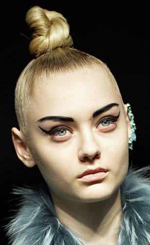 <p><strong>The look:</strong> Tightly coiled topknots paired with severe eyebrows and ultra-winged black eyeliner flicks. There's nothing soft about this look other than the nude lip.</p>