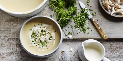 cream of chicken soup served from a large pan into a small bowl with a jug and chopped herbs to garnish