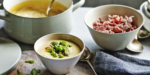 Split pea and ham soup in bowl with fresh mint alongside bowl of shredded ham