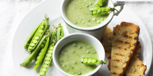 Pea soup with courgette, garlic and basil in white bowl with toast