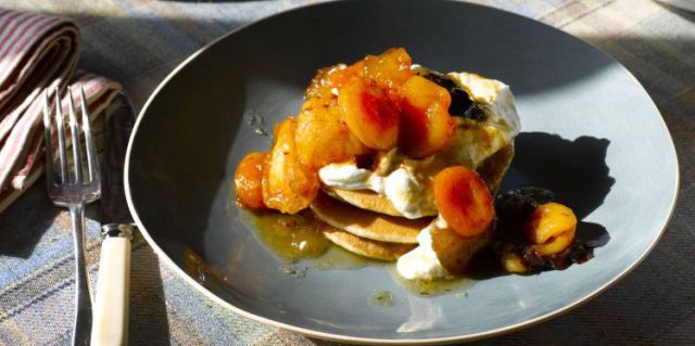 Stack of buttermilk pancakes on blue plate topped with yogurt and dried apricots