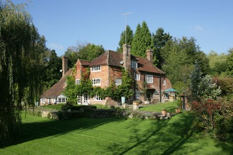 Exterior shot of the country house where Winnie the Pooh author lived surrounded by grass and trees