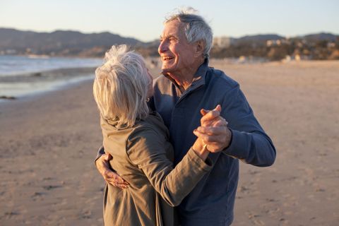 Old couple dancing on beach in winter