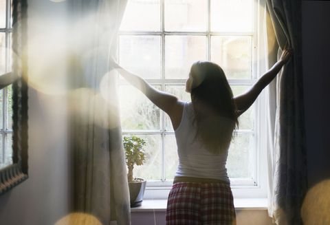 Morning person - woman opening curtains