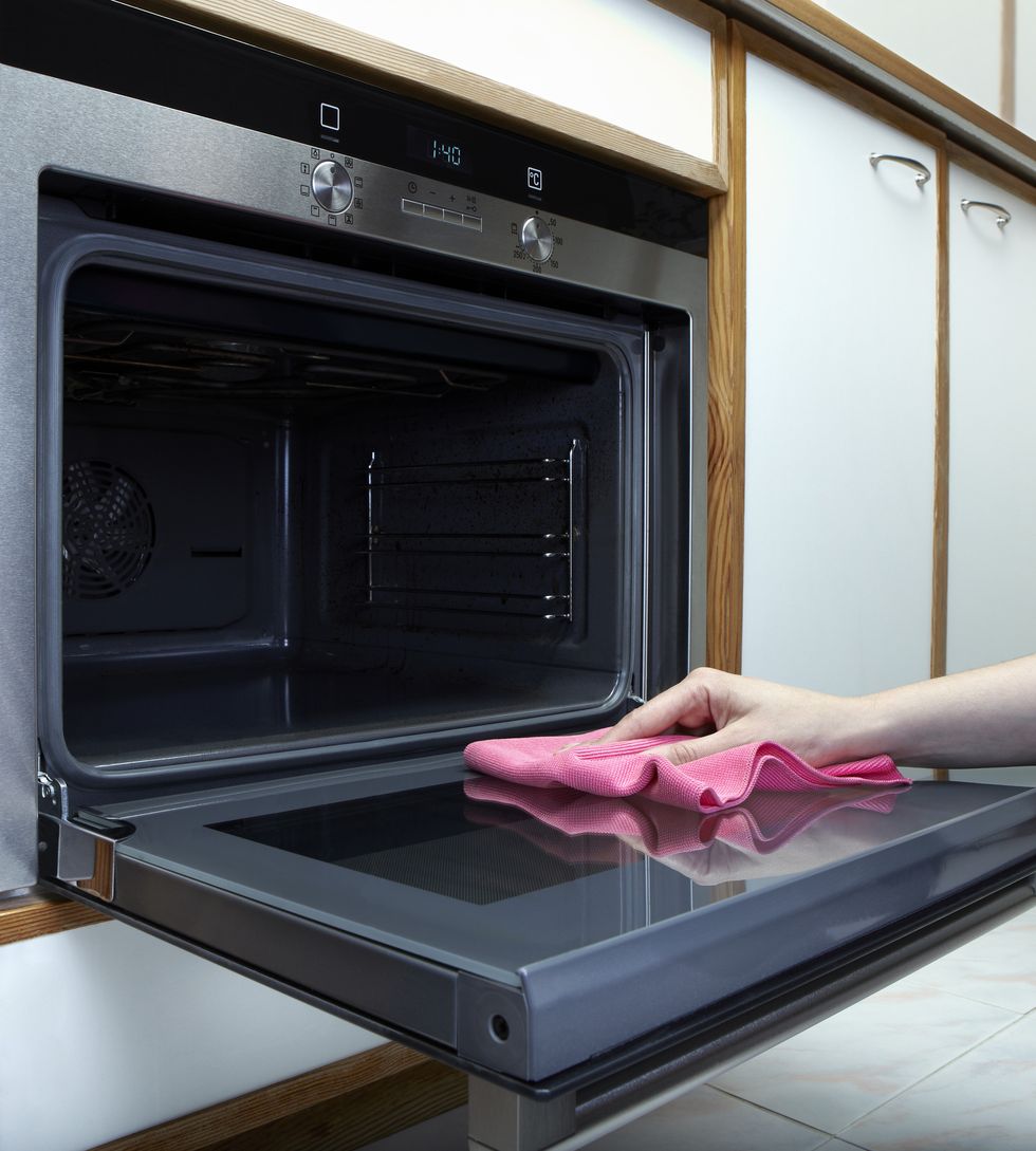 Women cleaning the oven with towel