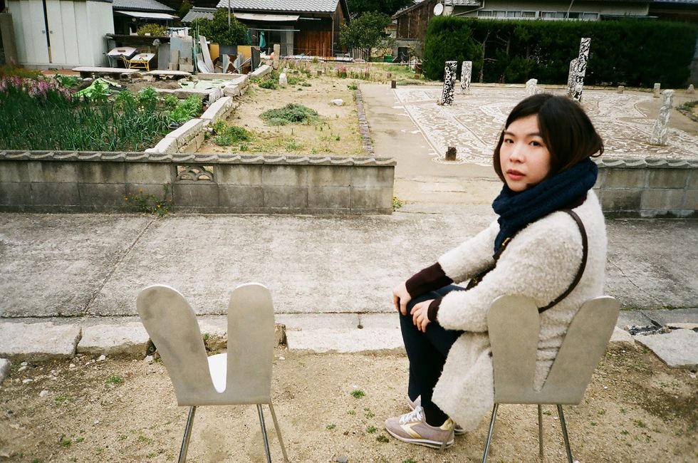 Sitting, Chair, Black hair, Street fashion, Outdoor furniture, Folding chair, Sweater, Lap, Scarf, Armrest, 