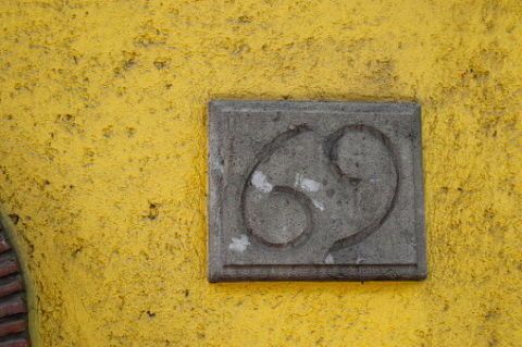 Yellow, Wall, Font, Number, Circle, Cement, Concrete, Symbol, Still life, Art, 