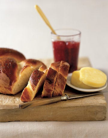sliced challah bread on a cutting board with butter and jam