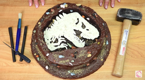 <p>You don't have to be Ron-Ben Israel to conquer this cake: <a target="_blank" href="http://cookiescupcakesandcardio.com/?p=6607">Cookies, Cupcakes, and Cardio</a> offers a printable template of the t-rex, so all you have to do is trace it using melted white chocolate in a piping bag.<strong> <a target="_blank" href="https://www.youtube.com/watch?v=rFv9SsATJ2o">See how it's done</a>.</strong></p>
