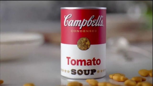 A can of Campbell's Tomato soup surrounding by Goldfish crackers.