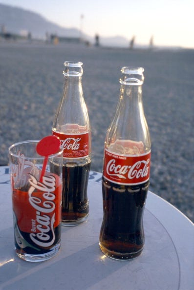 Glass, Bottle, Drinkware, Red, Drink, Carbonated soft drinks, Cola, Coca-cola, Metal, Flowering plant, 