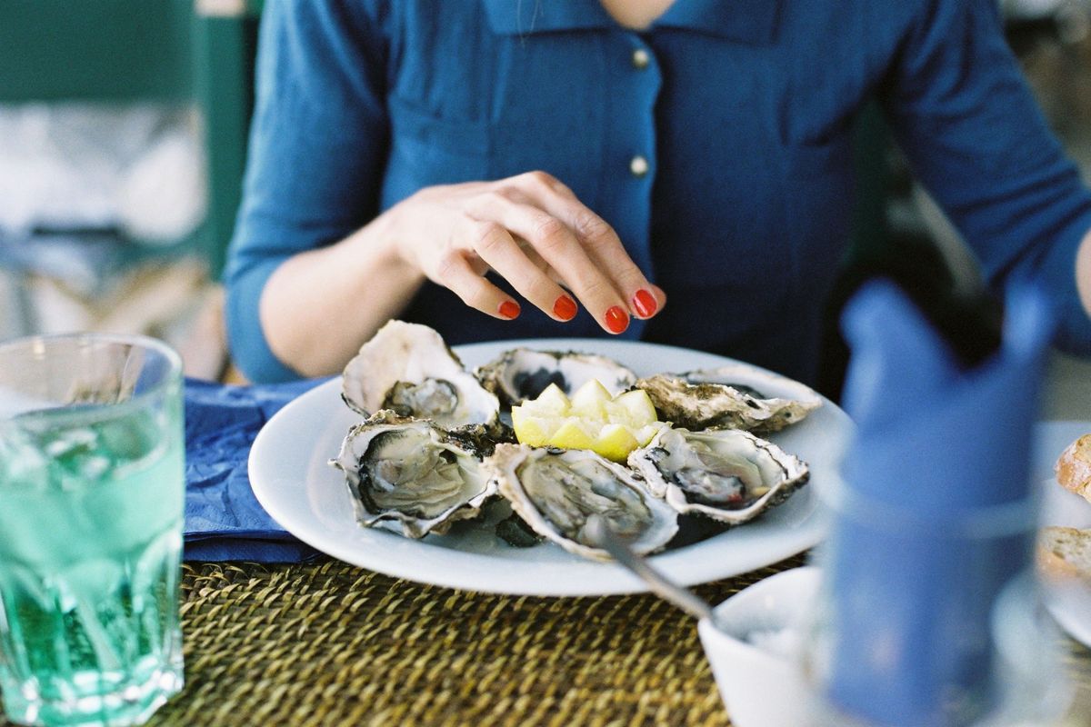 Woman eating raw oysters with lemon