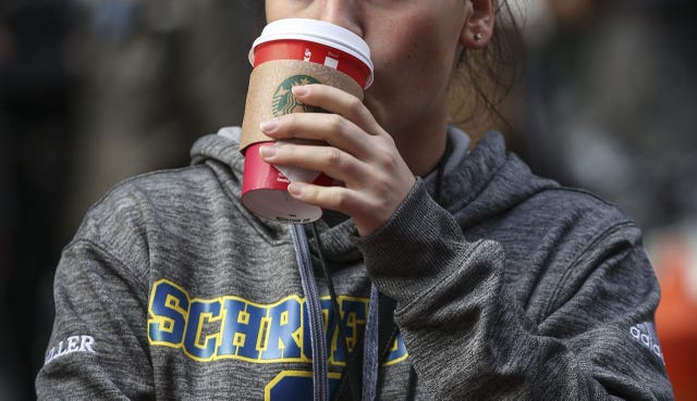 Woman drinking Starbucks coffee out of red cup